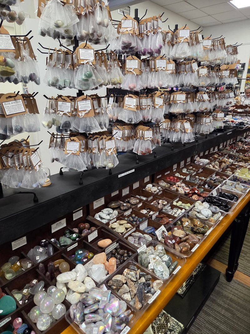 Wall display featuring large packaged crystal specimens, spiritual books, and tumbled stone inventory