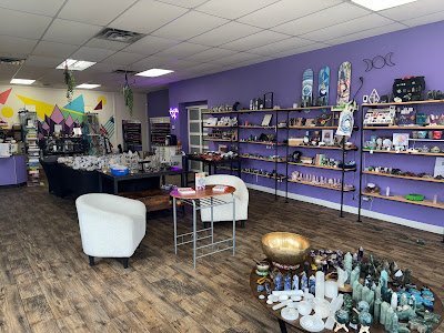 Shop interior showcasing books, crystals, and spiritual items with vintage blue chairs