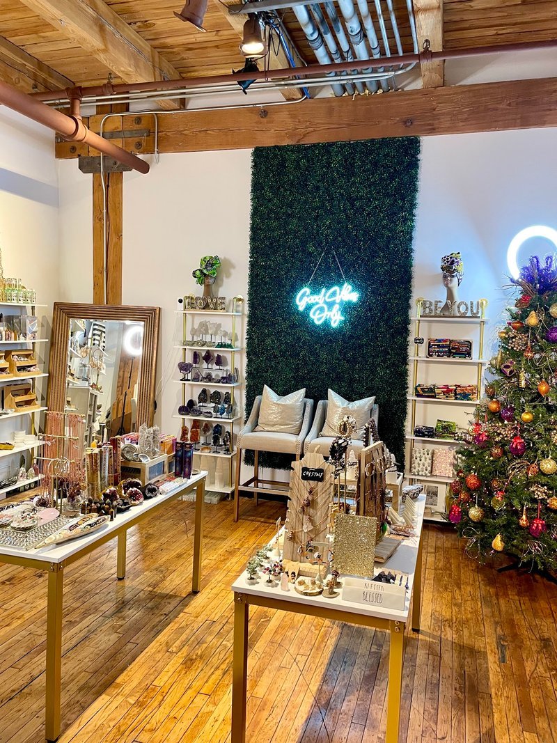 Purple wall display with wooden shelves featuring singing bowls, smoky quartz points, and succulents