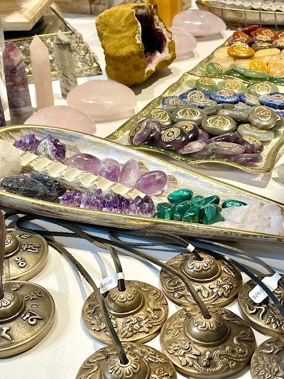 Minimalist retail display with orgonite pyramids, crystal spheres, and sage bundles on wooden shelving