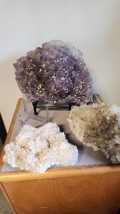 Purple amethyst geode on display stand with white calcite crystal specimens