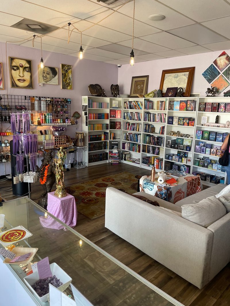 Metaphysical store interior with bookshelves, spiritual items, and comfortable seating area