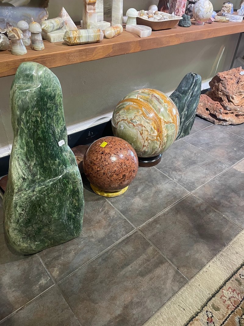 Large polished stone sculptures including green aventurine obelisk and jasper spheres