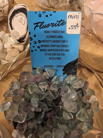 Tumbled fluorite stones in labeled display bowl with metaphysical properties card