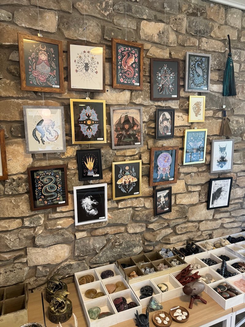 Stone wall gallery displaying framed spiritual artwork above crystal display boxes